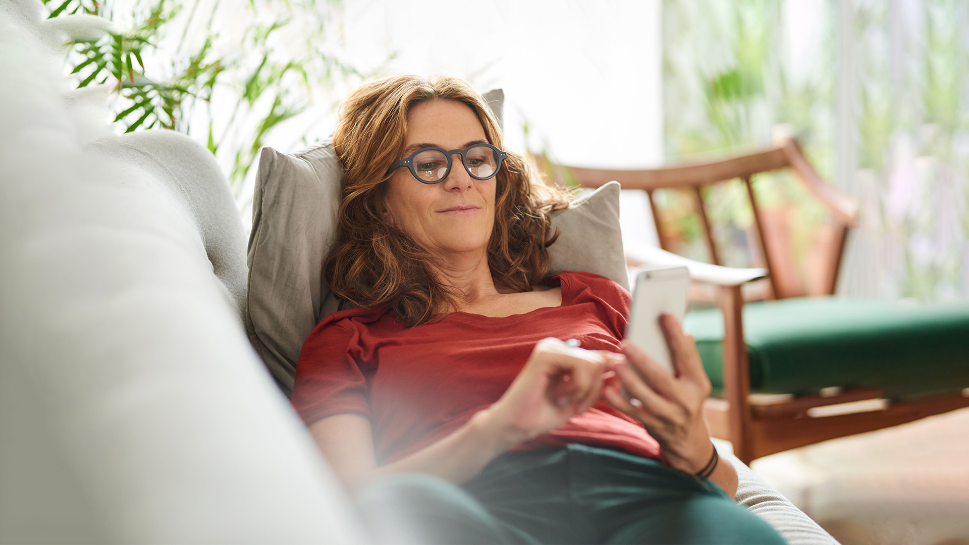 Frau mit Smartphone in der Hand auf Couch. Frau mit Smartphone in der Hand auf Couch.