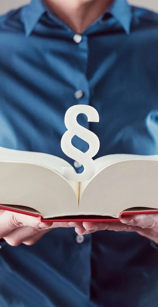 Mann hält aufgeklapptes Gesetzbuch in den Händen. 