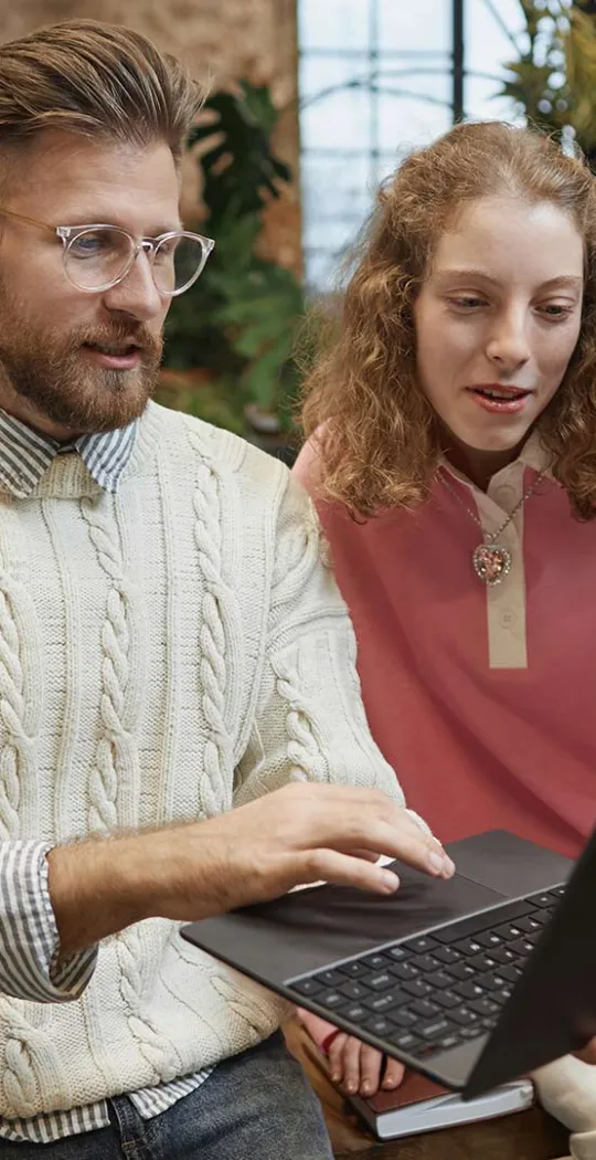 Junge Menschen schauen gemeinsam auf einen Laptop. 