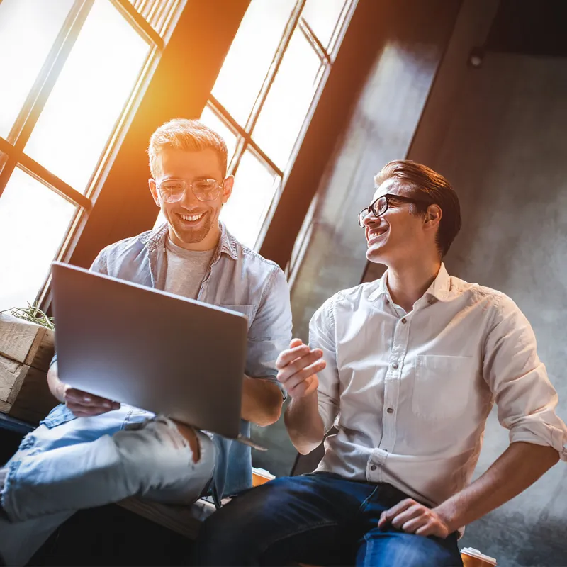 Zwei Männer sitzen auf einem Tisch und sind im Gespräch miteinander.