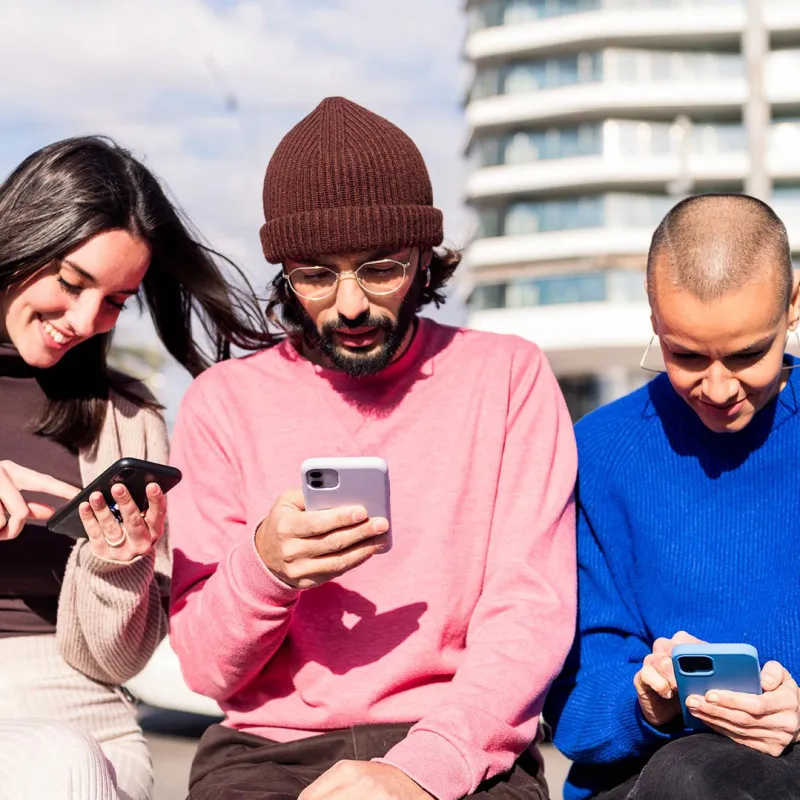 Junge Menschen sitzen zusammen und sind am Smartphone. 