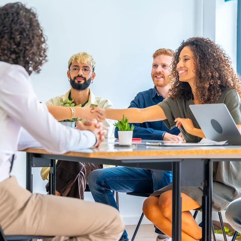 Gruppe junger Menschen sitzt an einem Konferenztisch.