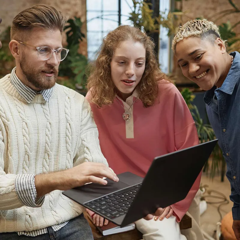 Junge Menschen schauen gemeinsam auf einen Laptop. 