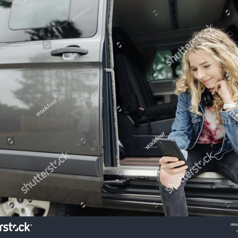 Junges Mädchen sitzt im Auto am Handy 